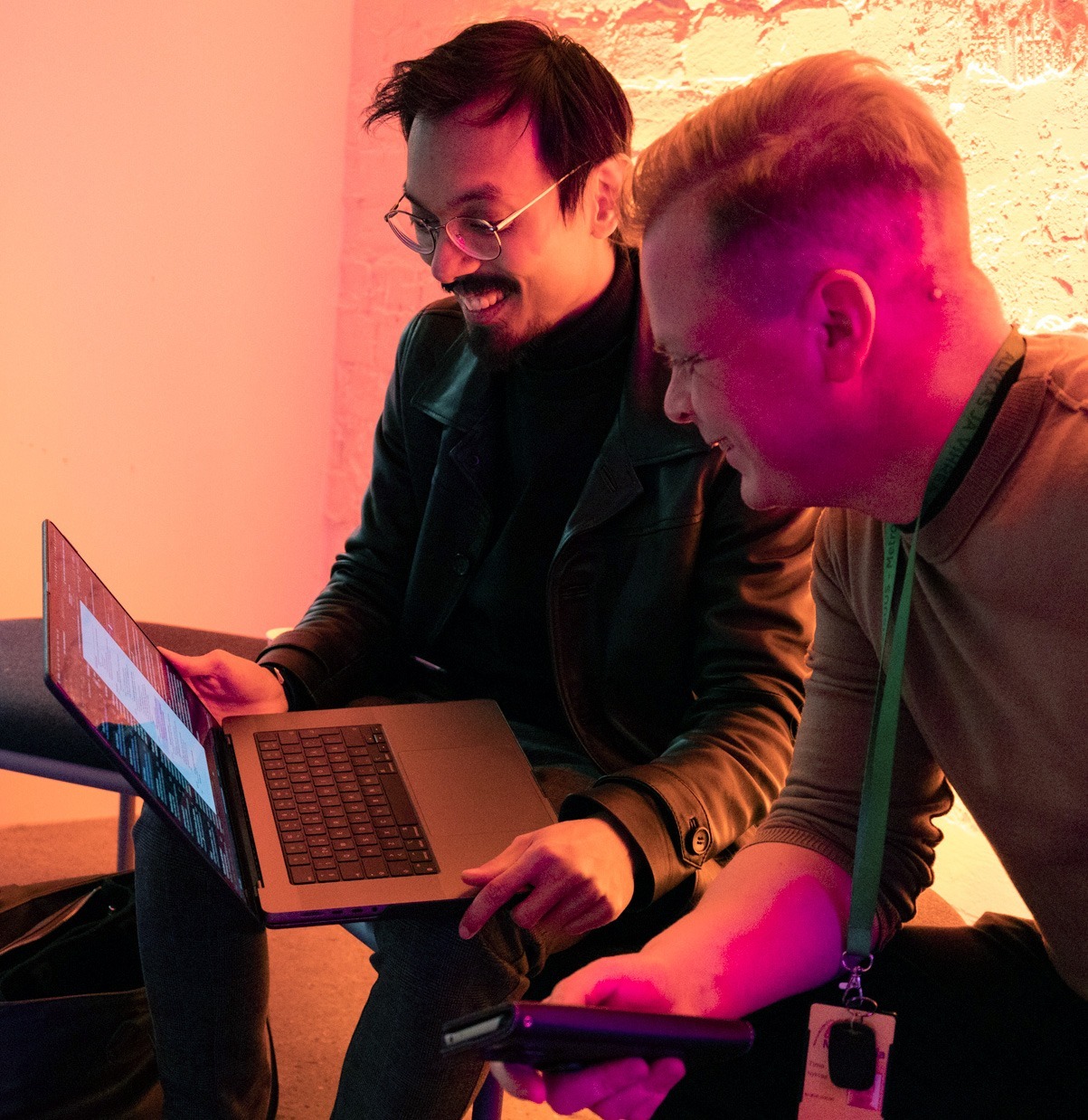 Two people watching something on computer and smiling,